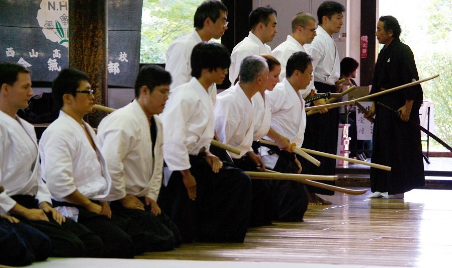 Traditional Japanese martial arts practitioners kneeling together during weapons practice at a dojo